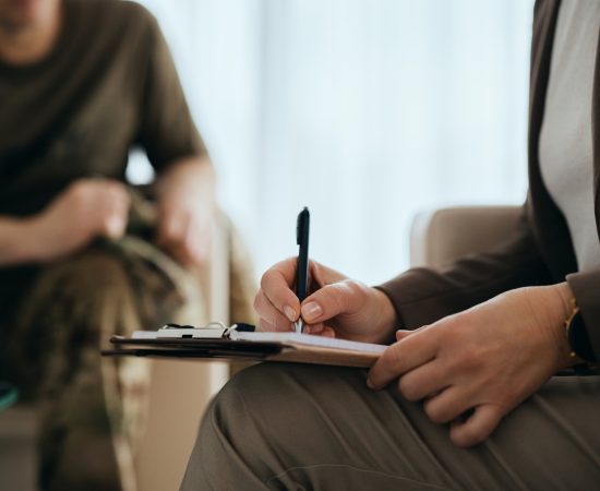 Close up of psychotherapist takes notes during counseling with soldier. Close up of psychotherapist takes notes during counseling with soldier.